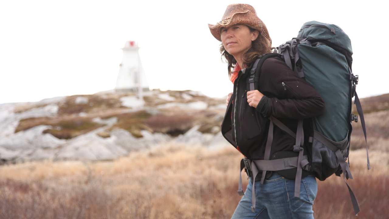 a woman with a backpack in front of a lighthouse